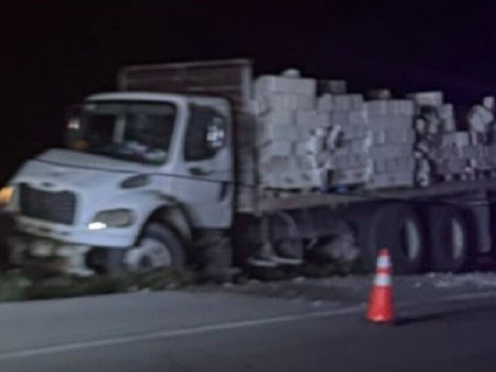 Un camión cargado con material de construcción sale de la carretera en el entronque de Motul