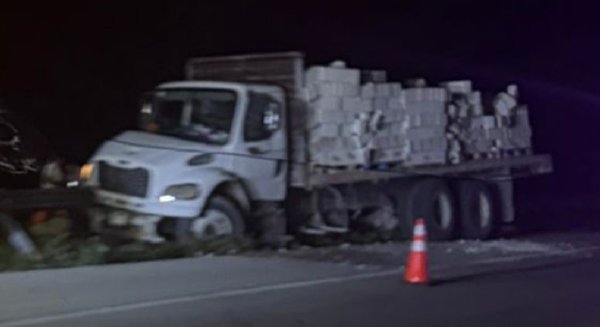 Un camión cargado con material de construcción sale de la carretera en el entronque de Motul